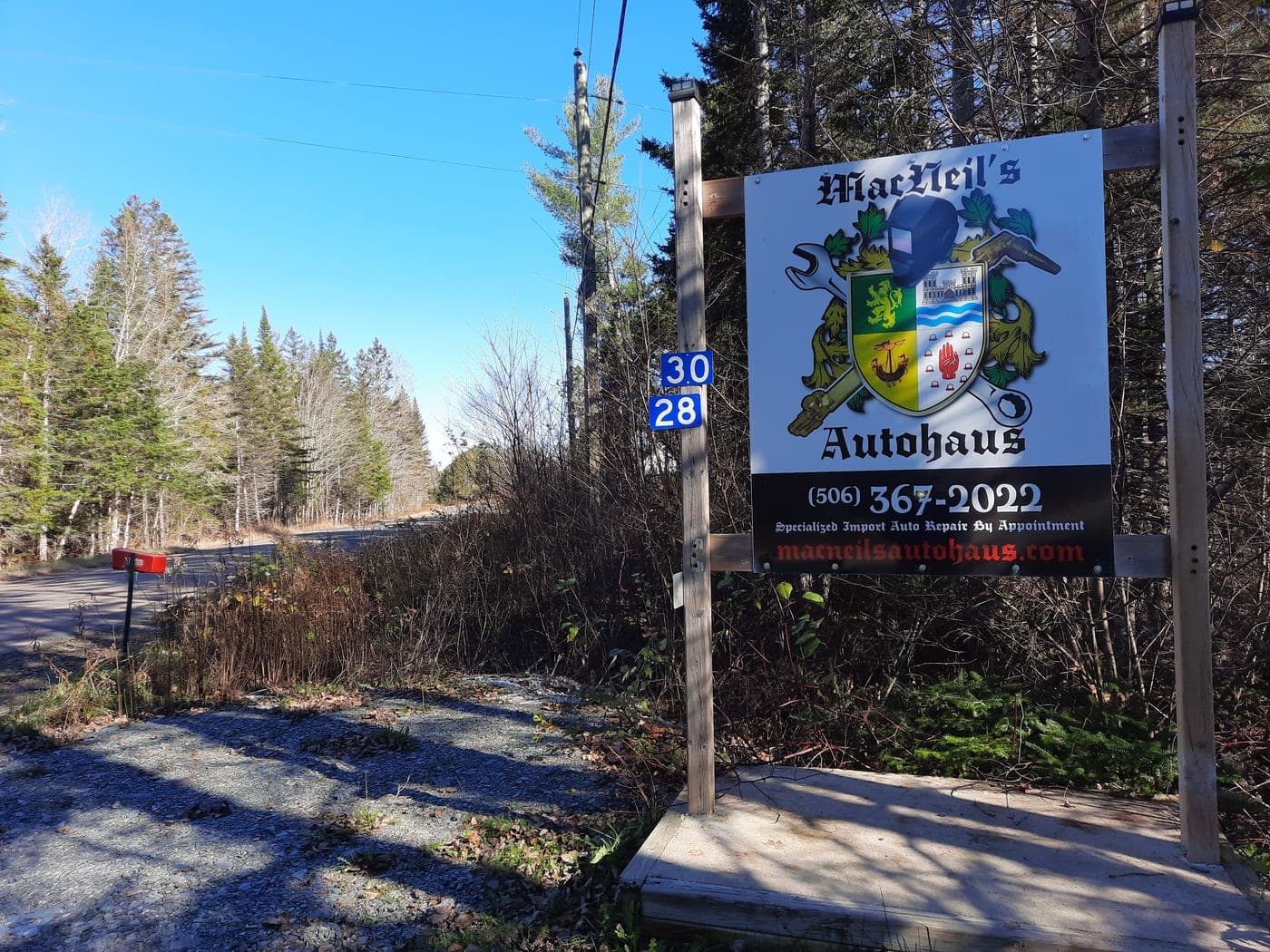 The MacNeil’s AutoHaus crest sign at the wooded entrance off Nashwaak Road