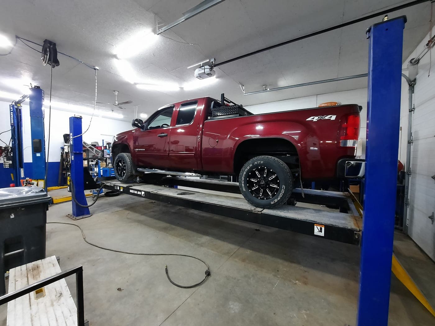 A pickup truck on the hoist in the brightly lit service bay