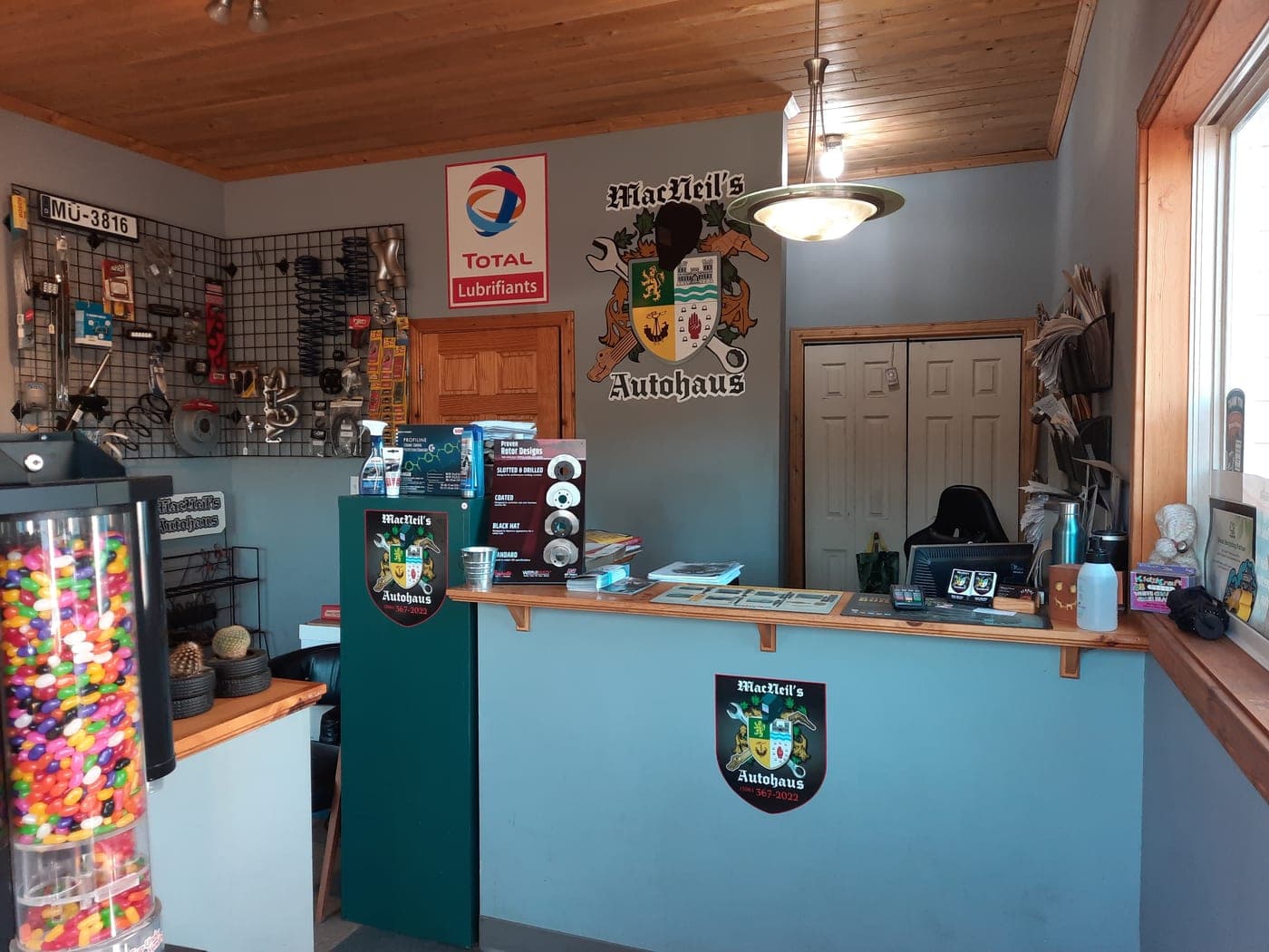 The front desk and customer lounge at MacNeil's AutoHaus, the shop crest mounted on the counter wall